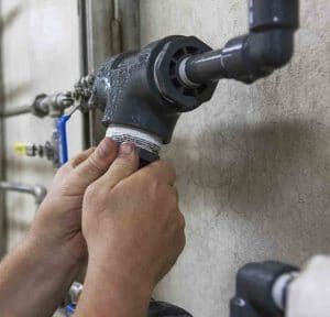 A person is fixing a pipe on a wall.