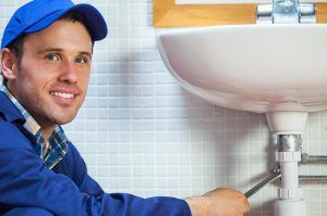 A plumber is fixing a sink in a bathroom.