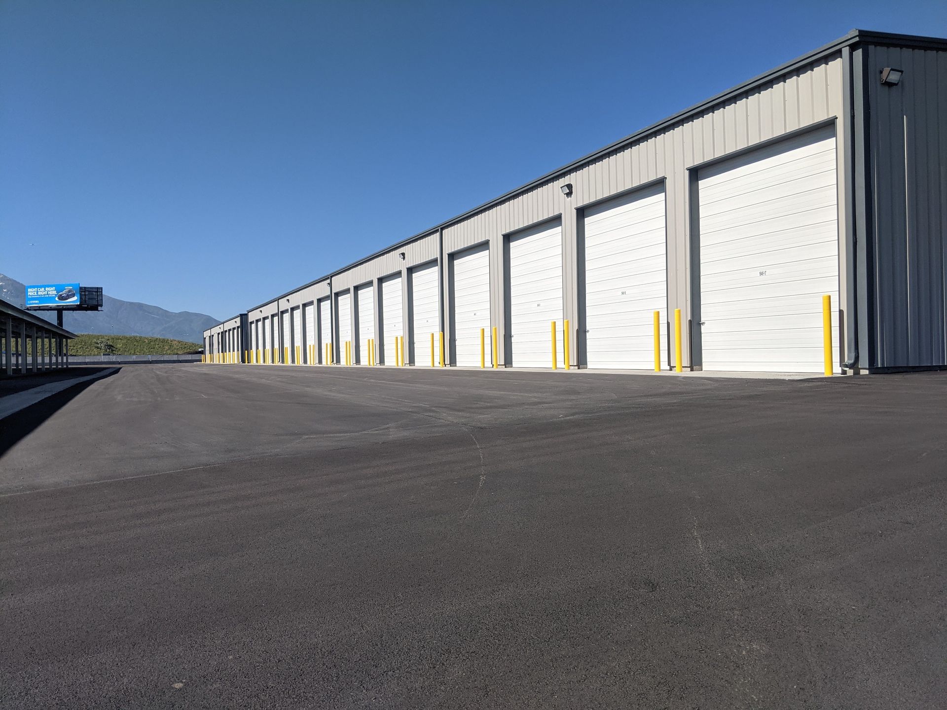 A row of storage units along a road under a blue sky