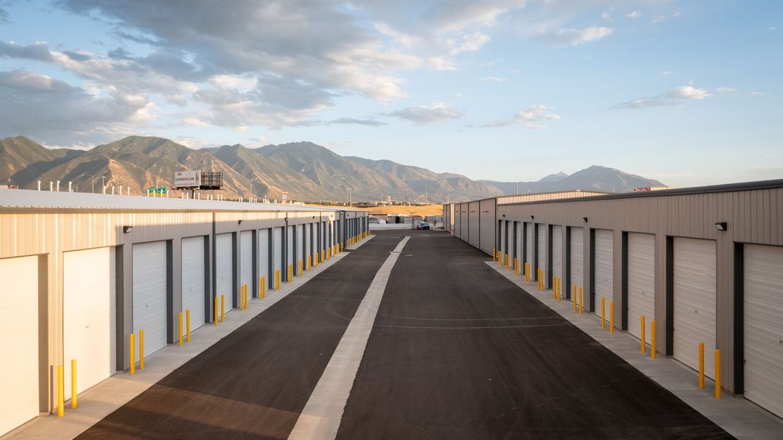 A road going through a storage facility with mountains in the background.