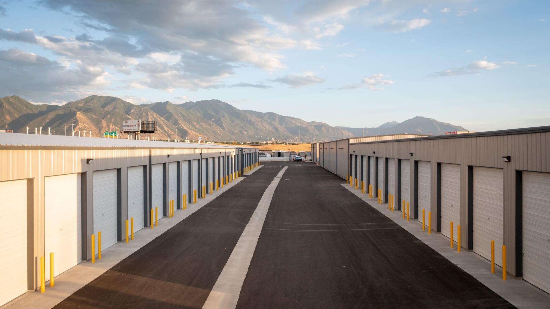 A road going through a storage facility with mountains in the background.
