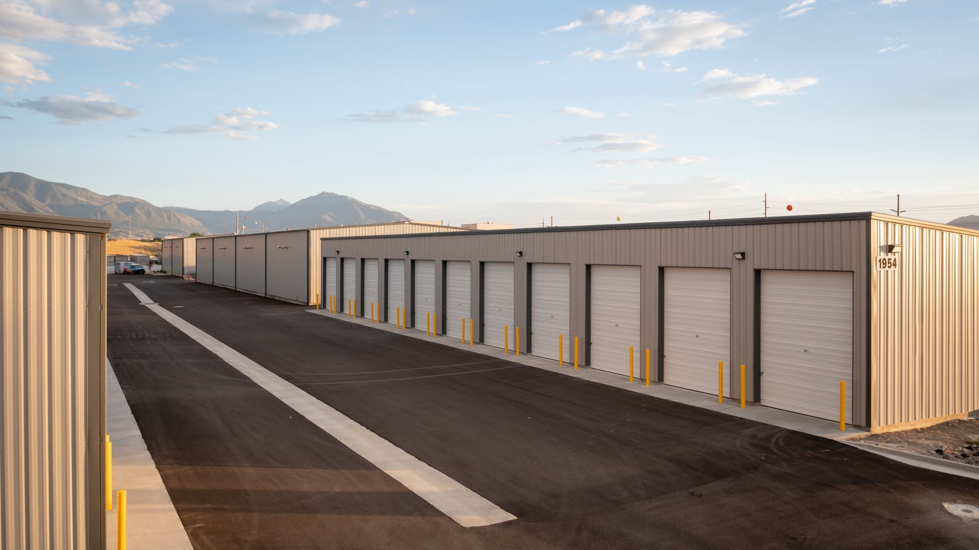 A row of storage units along a road with mountains in the background.
