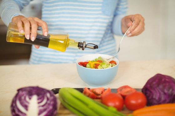 woman making a salad with olive oil