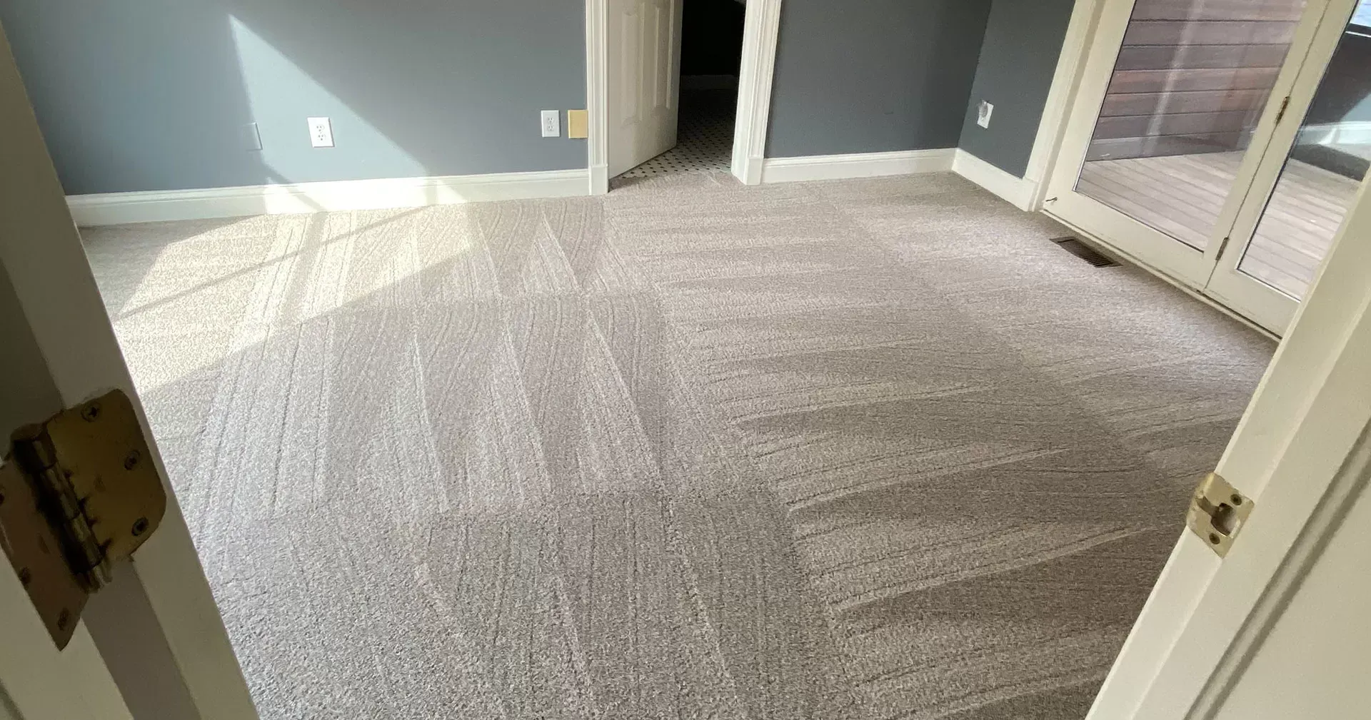 Empty room with light gray carpet, blue-gray walls, white trim and double doors.