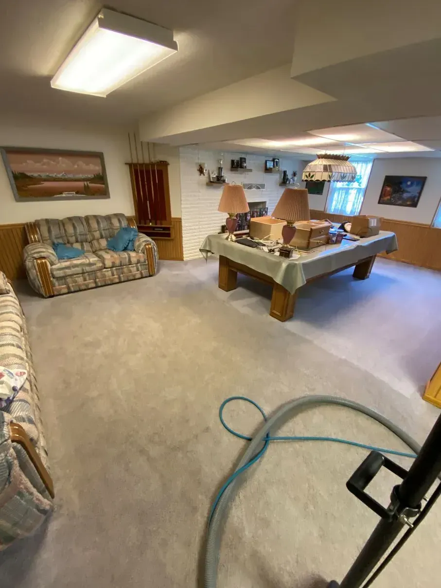 Basement with a pool table, two sofas, and carpet being cleaned by a machine.