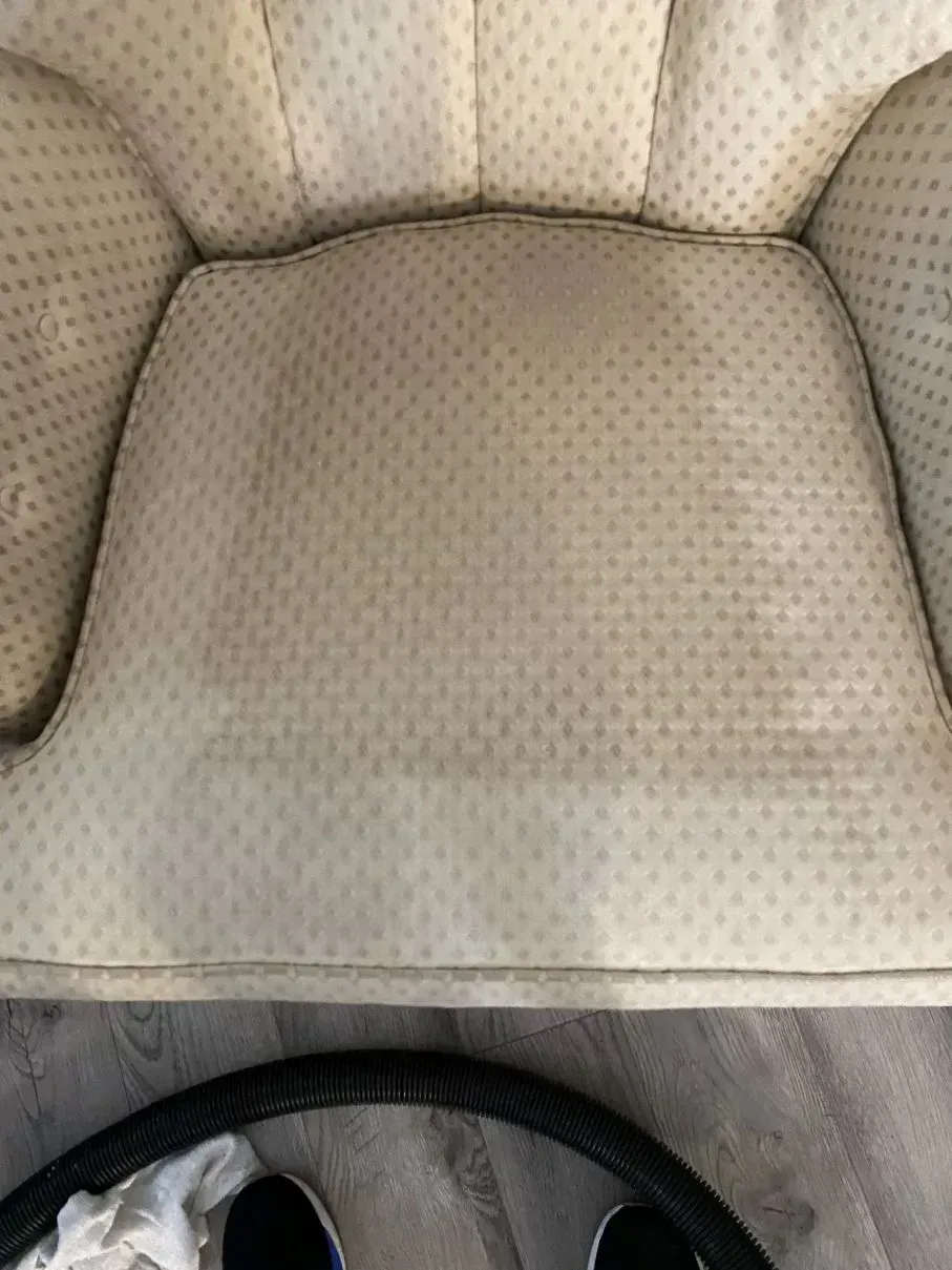 Beige upholstered armchair, showing stains on the seat and back.