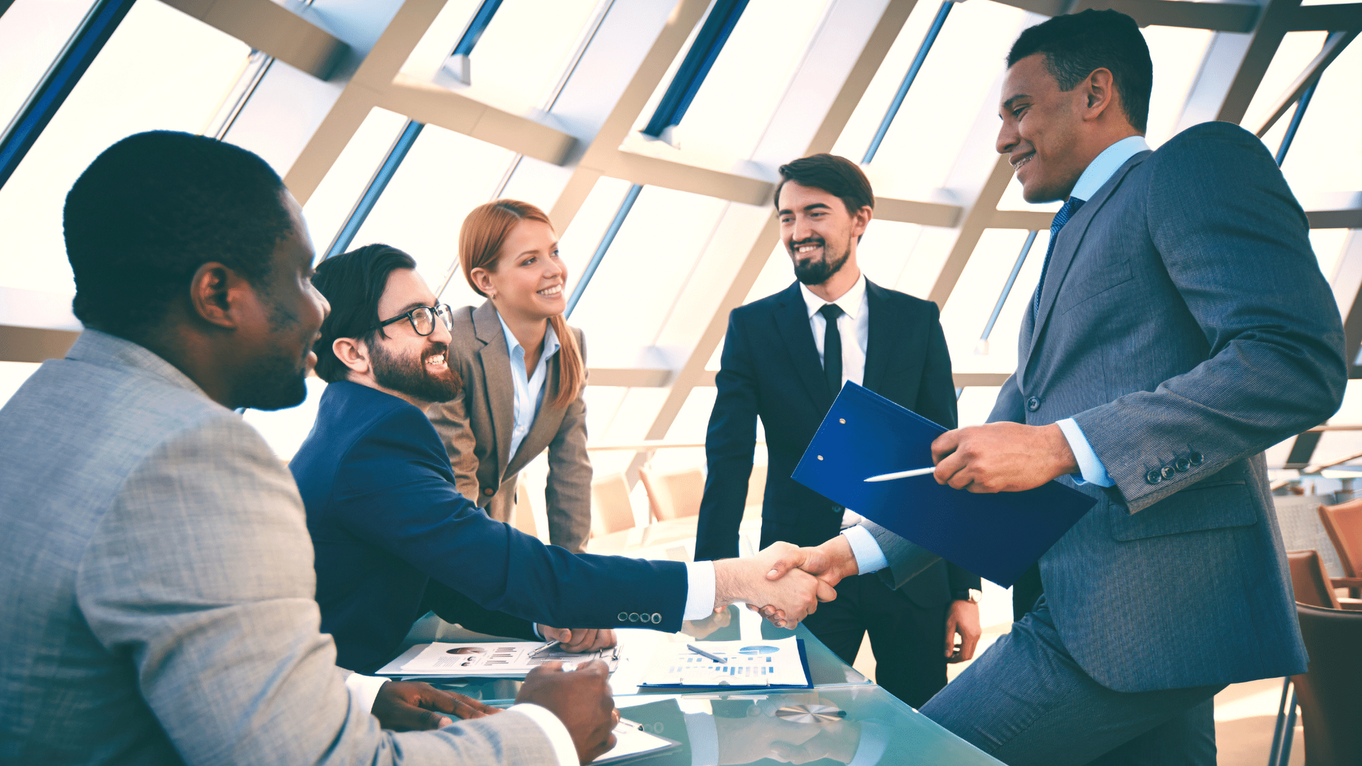 A group of business people are shaking hands in an office.