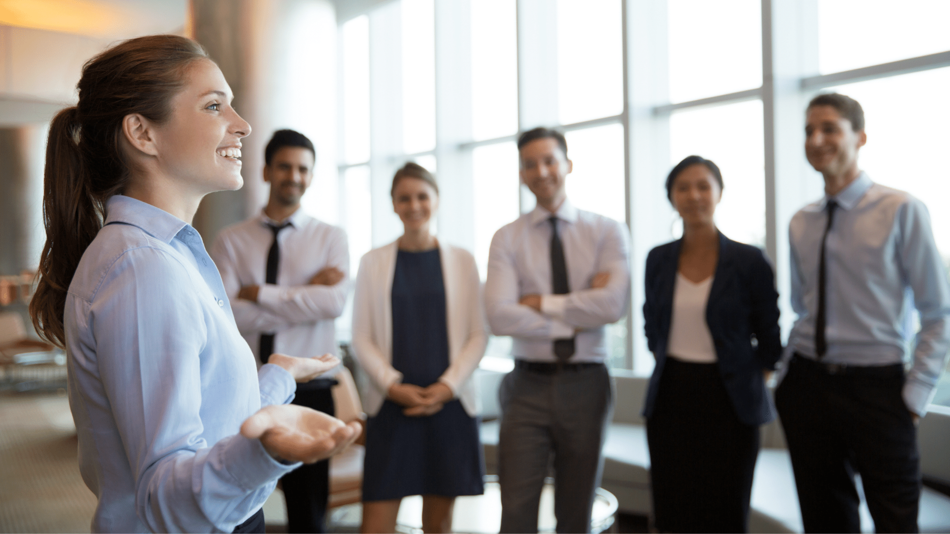 A woman is standing in front of a group of business people.