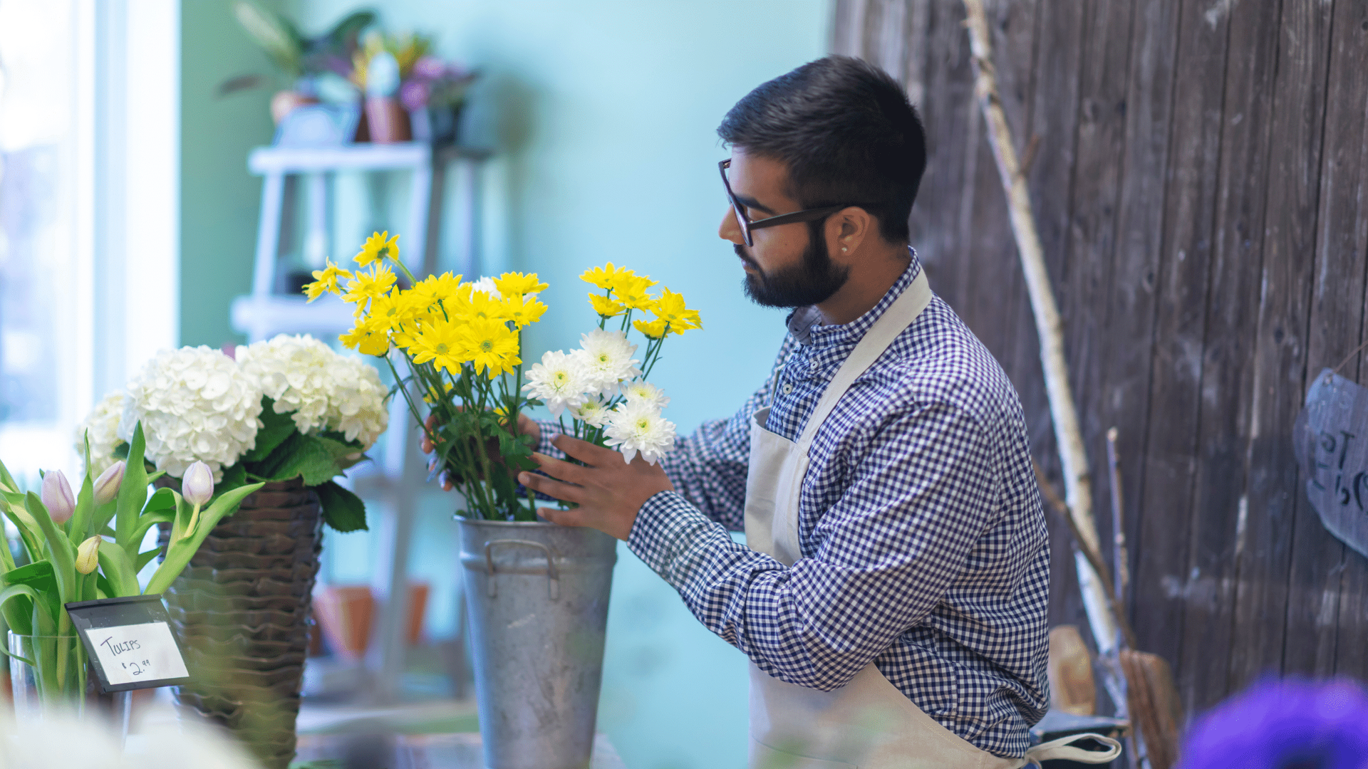 A man is arranging flowers in a vase in a flower shop.