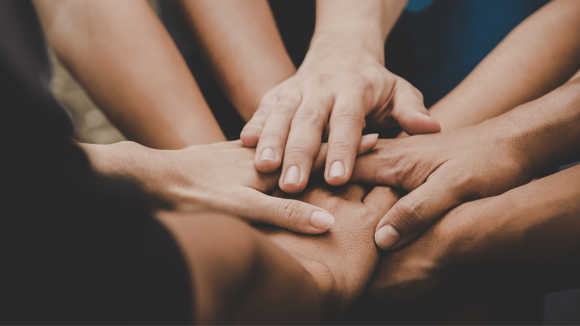 A group of people are putting their hands together in a circle.