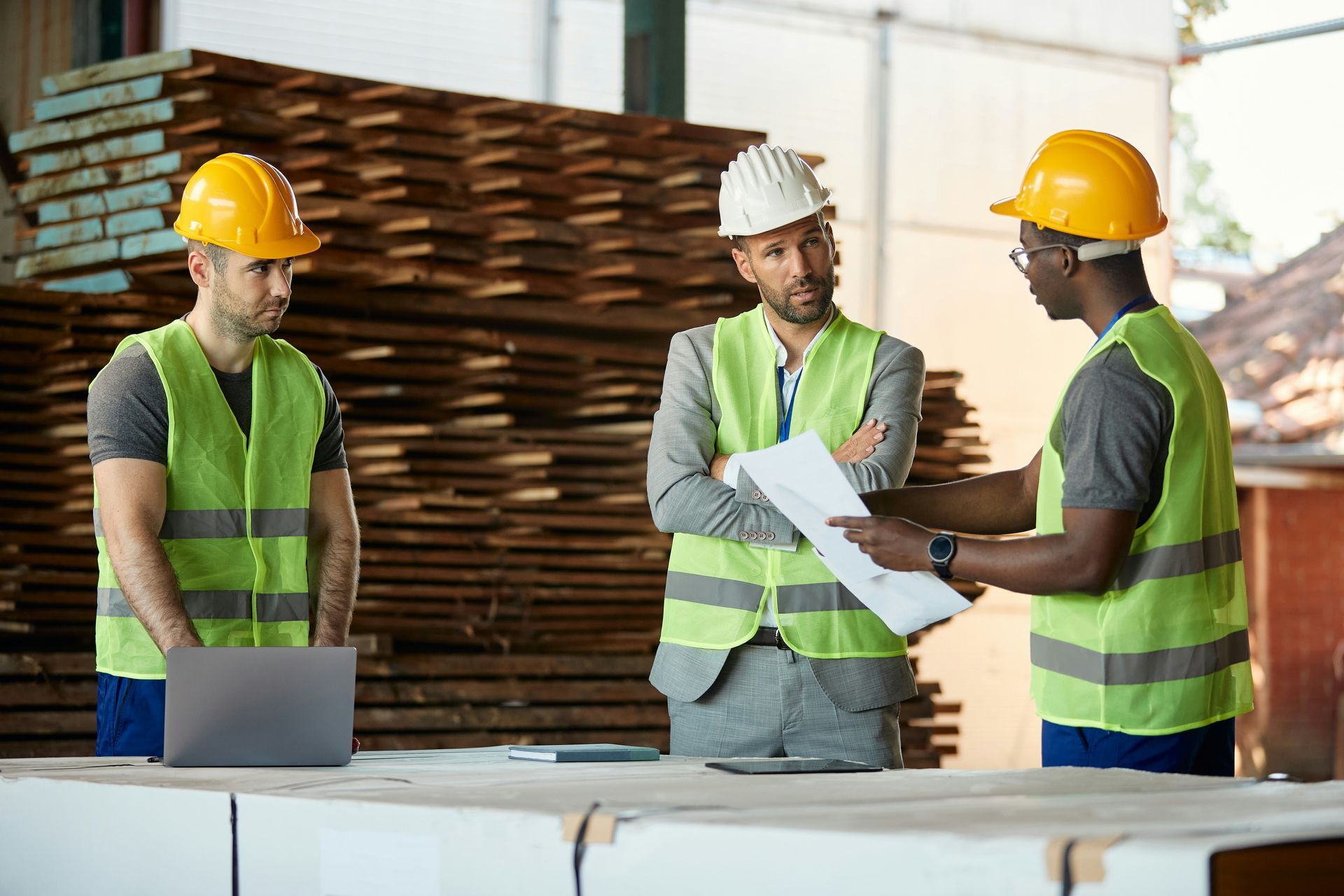 A group of construction workers are standing in a warehouse looking at a blueprint.