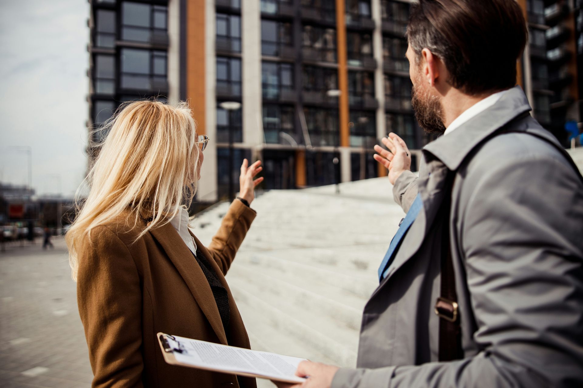 A man and a woman are talking to each other in front of a building.