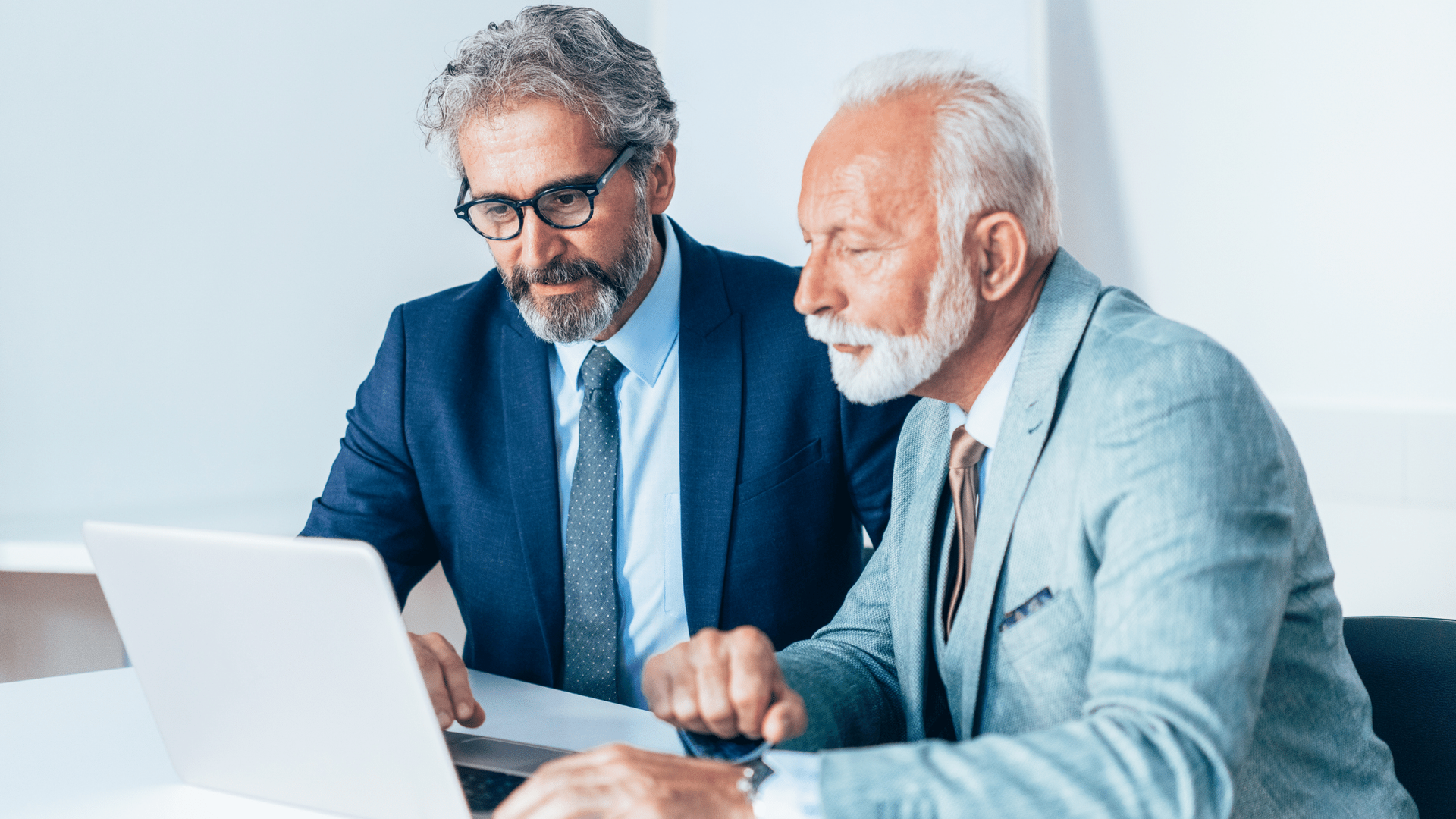 Two men are looking at a laptop computer together.