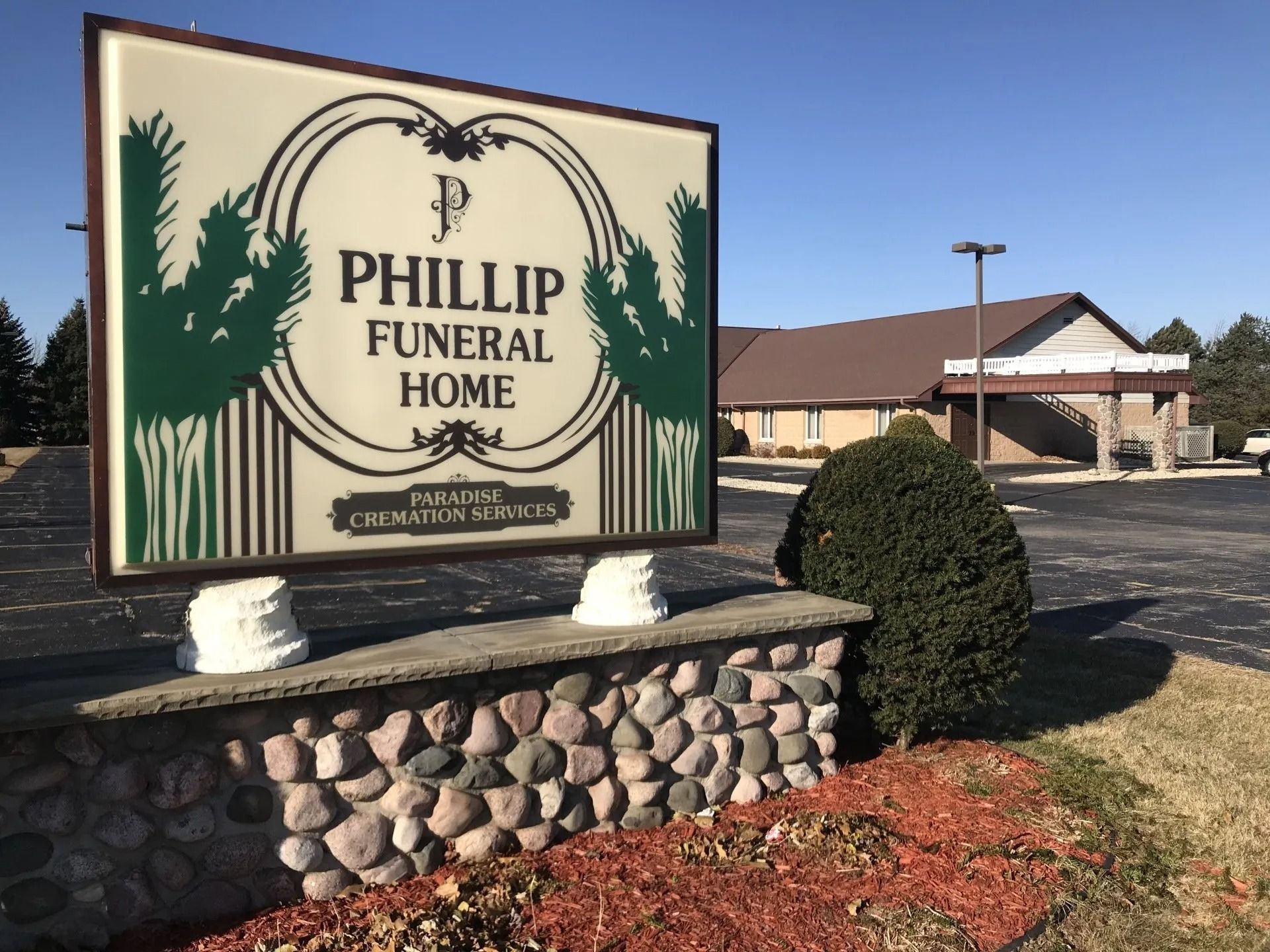 Sign for Phillip Funeral Home, brown building in the background, blue sky.