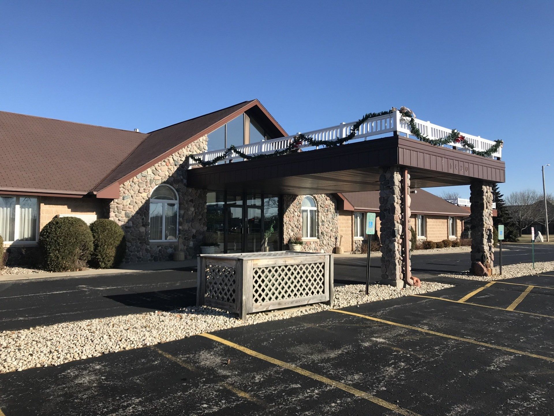 Stone-faced building entrance with a canopy. Decorations on canopy, parked cars in front.