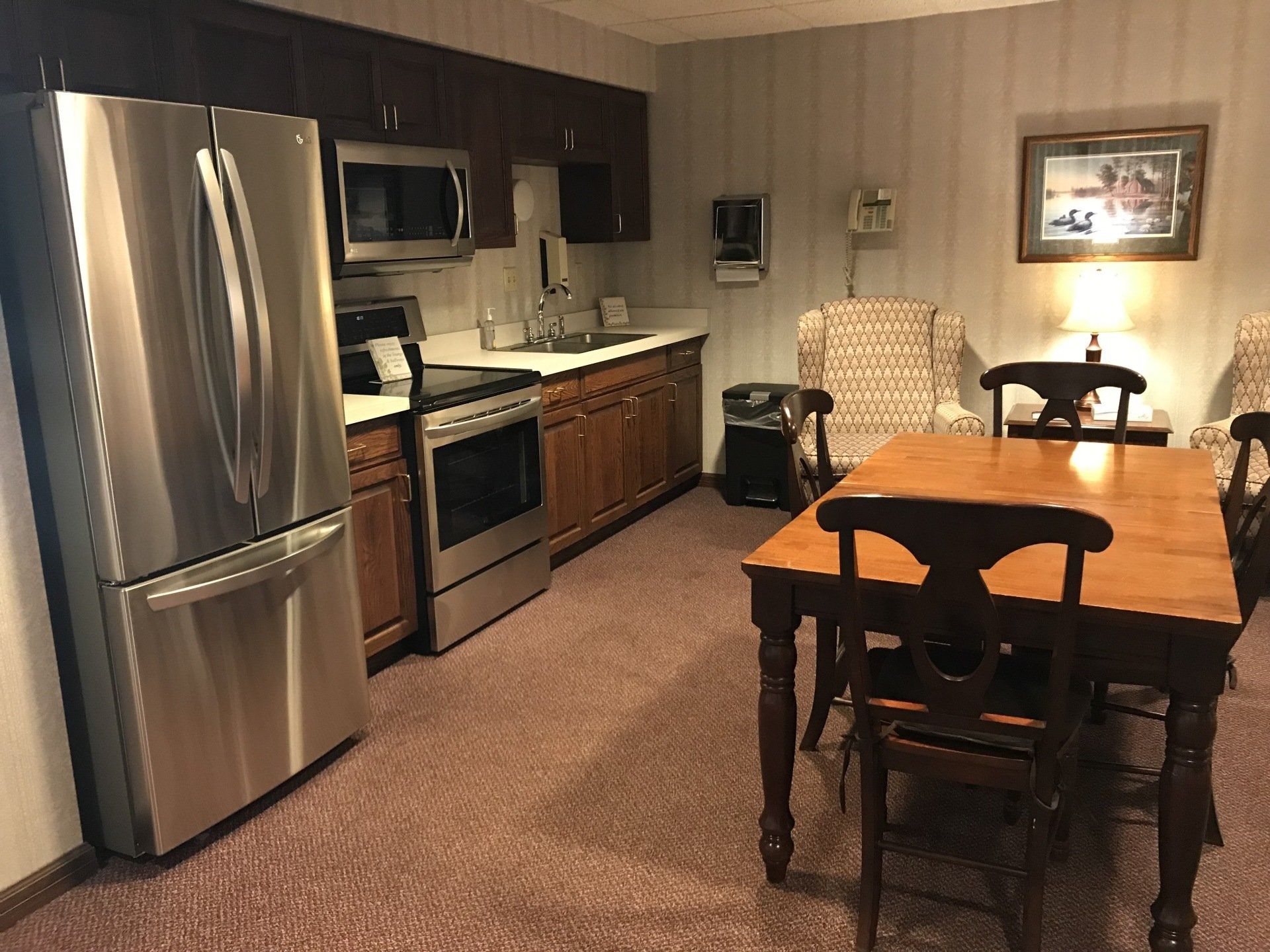 Kitchen area with stainless steel appliances, wood cabinets, and a dining table.