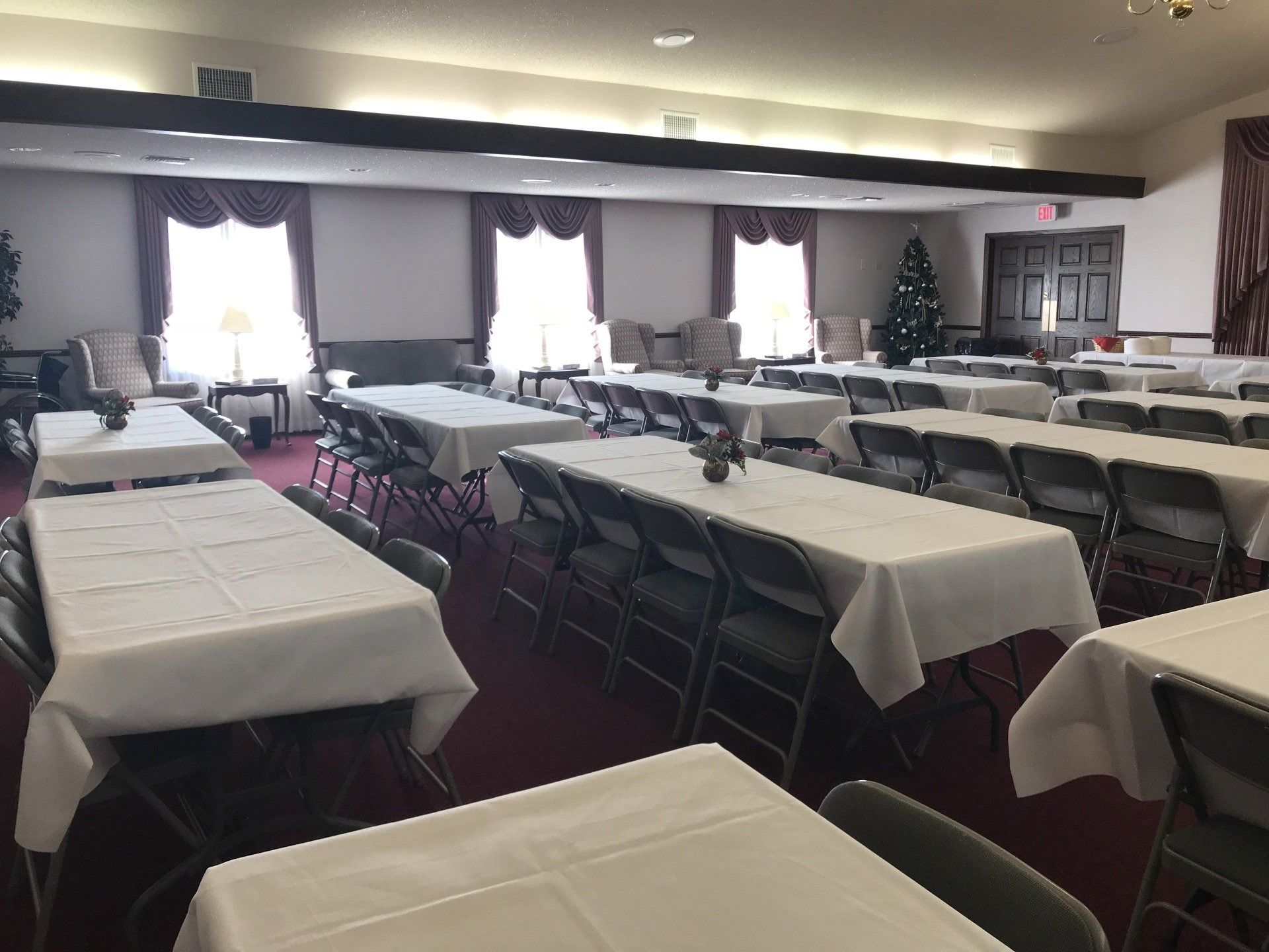 Banquet hall with white tablecloths, chairs, and Christmas tree.