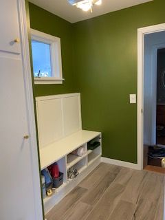 White wainscoting on wall with electrical box and dark wooden door.