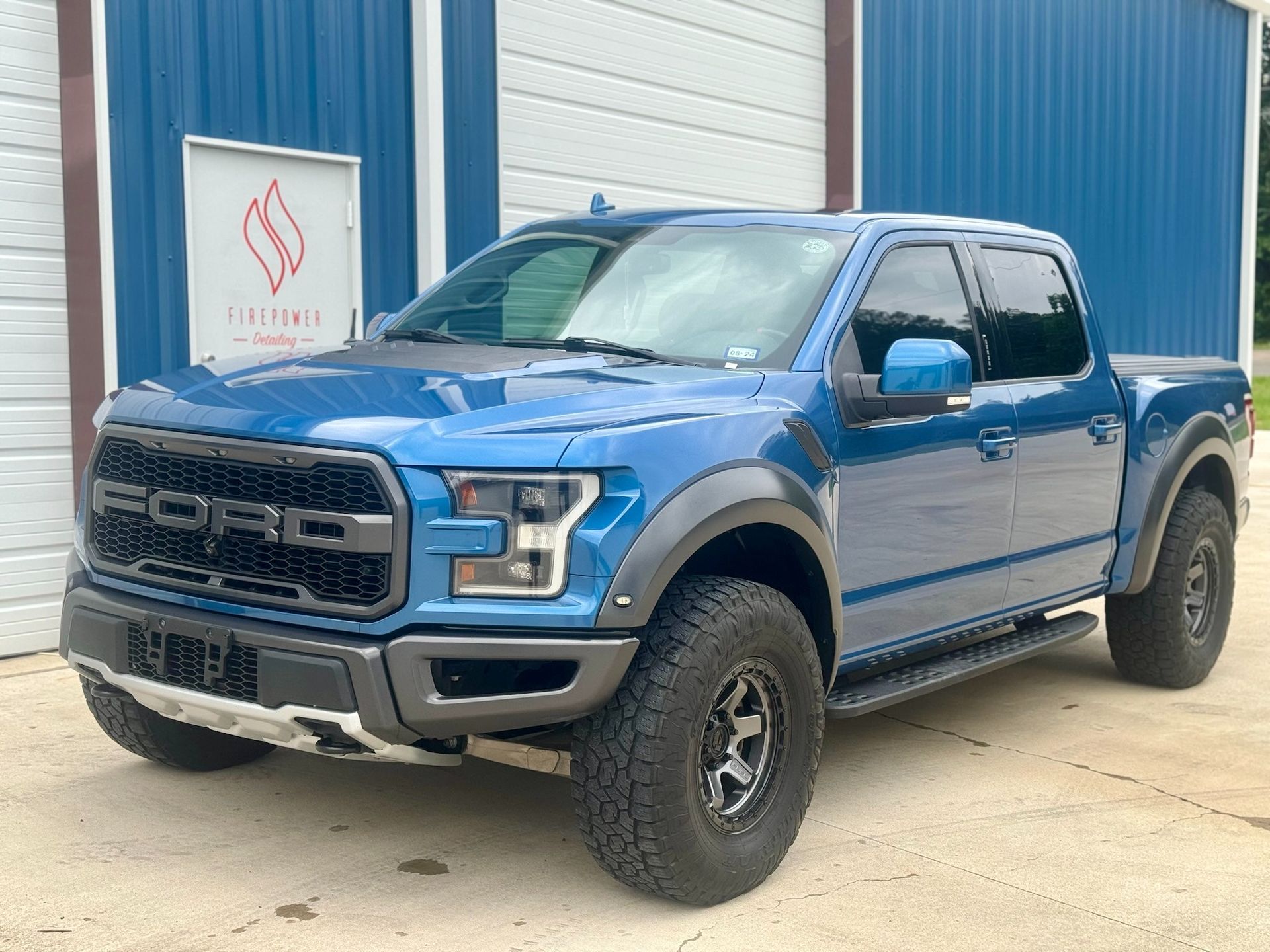 A blue truck is parked in front of a blue building.