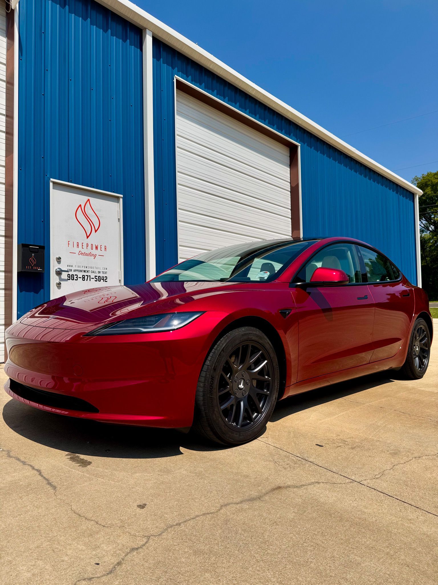 A red pickup truck is parked in front of a blue building.