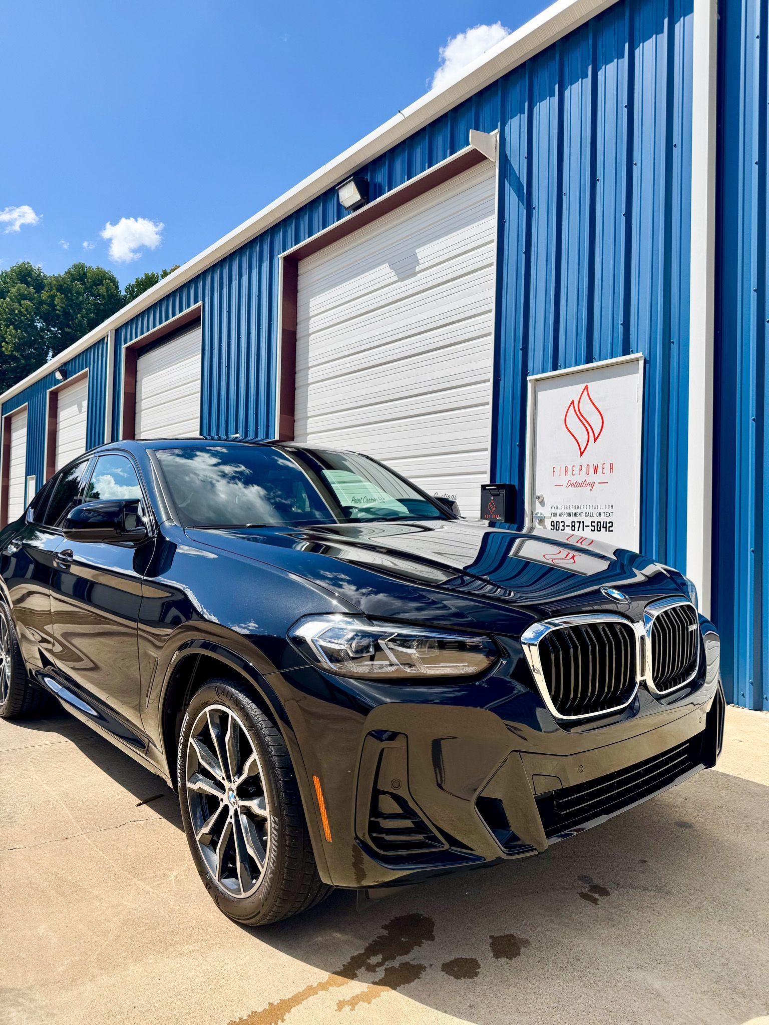 A silver truck is parked in front of a blue garage door.