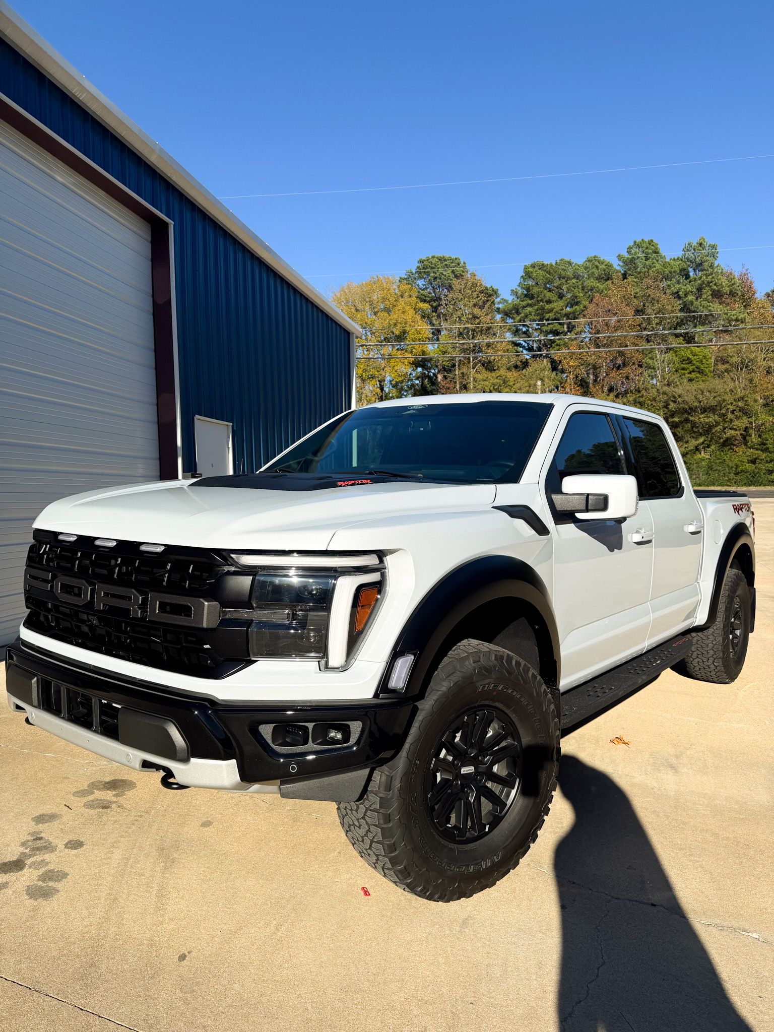 A red pickup truck is parked in front of a blue building.