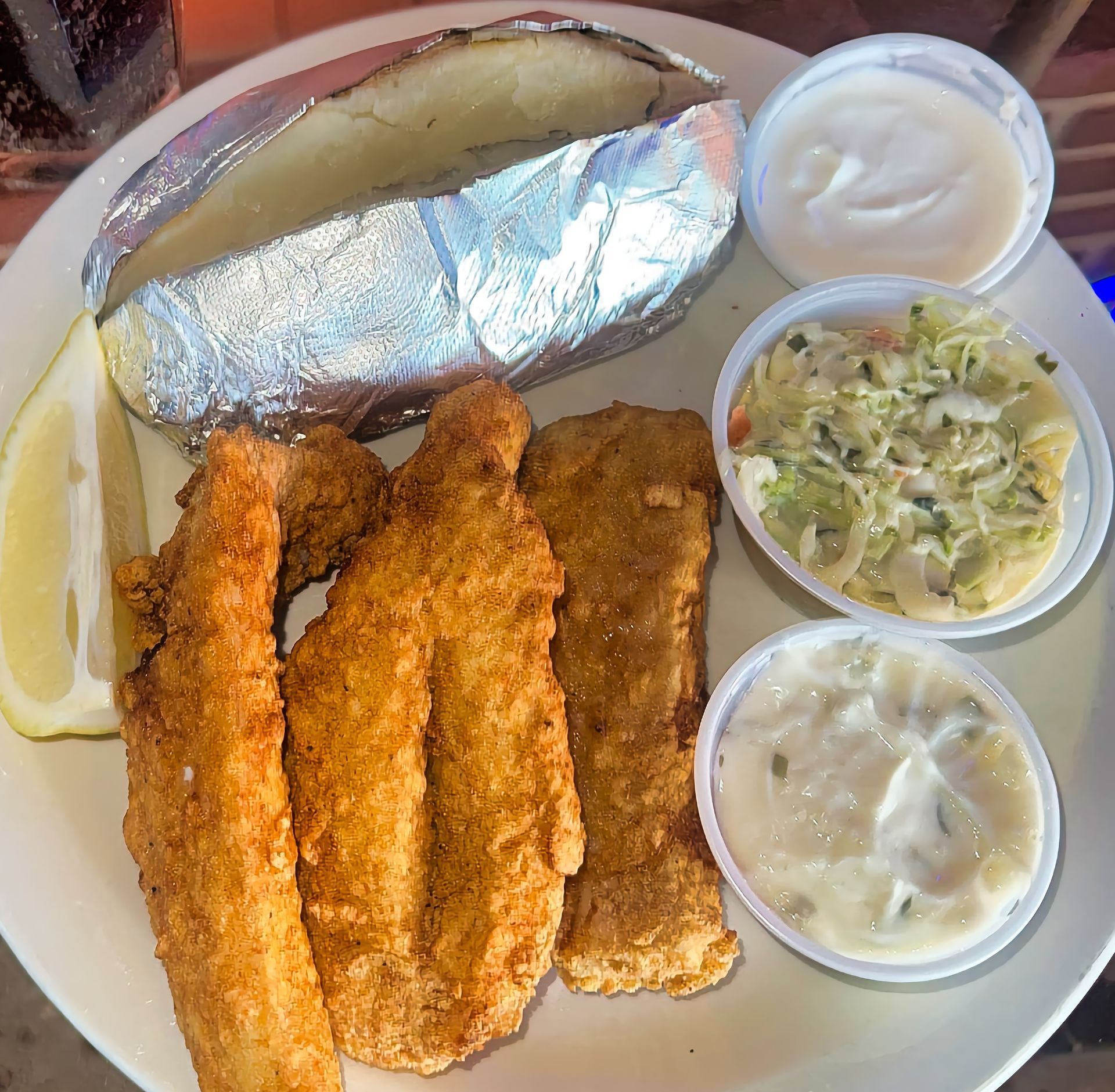 Friday fish fry plate with fried fish, baked potato, lemon, and sides at Three Dockers