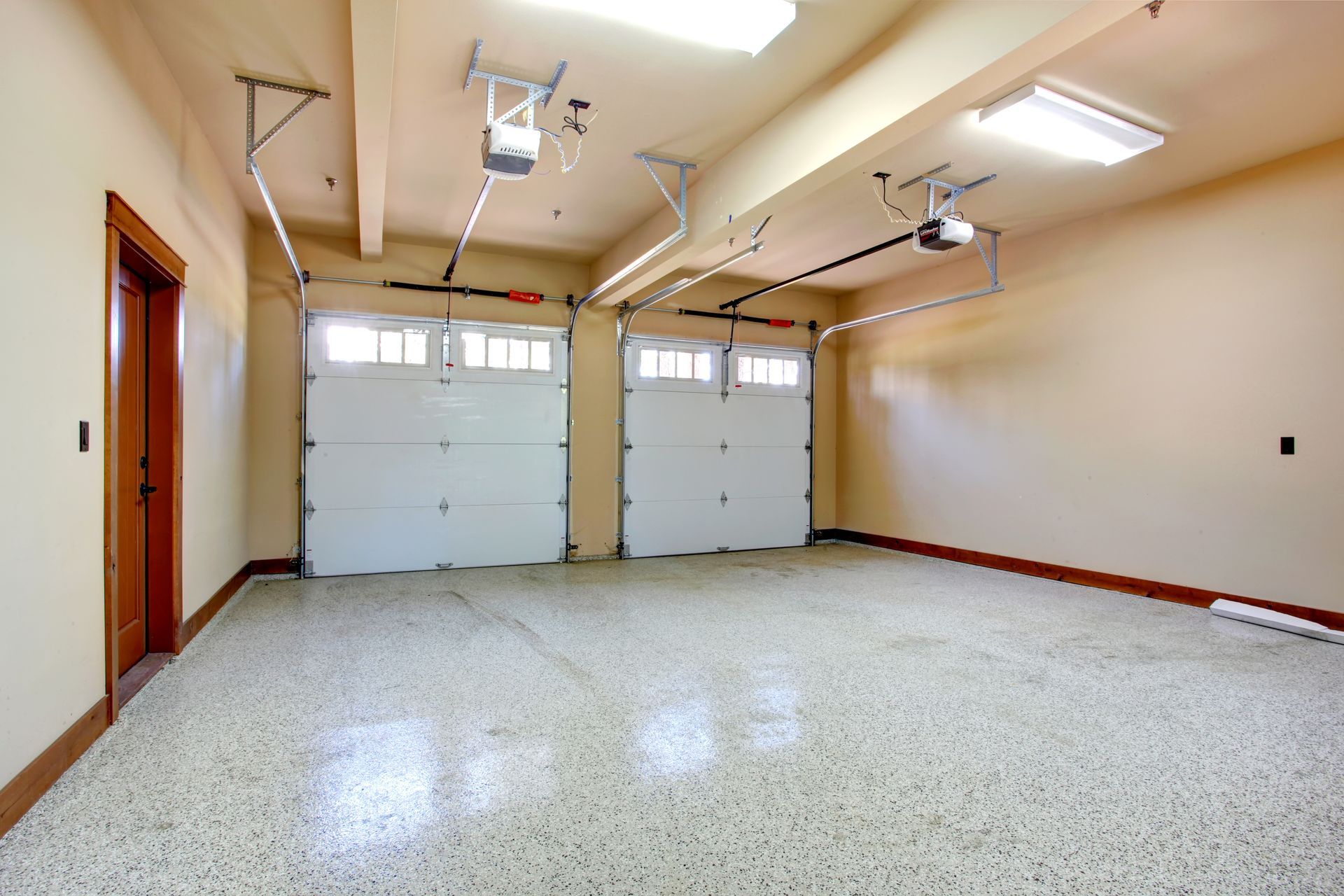 Empty garage with white doors and speckled flooring.