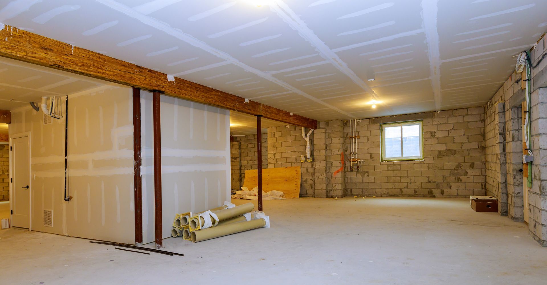 An empty basement with drywall and a window.