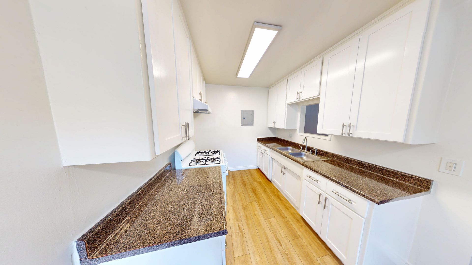 White kitchen with brown countertops and wooden floors.