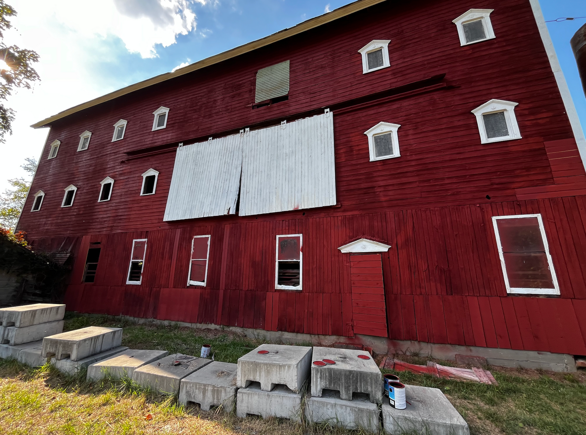 A large red barn with white windows is sitting in the grass.
