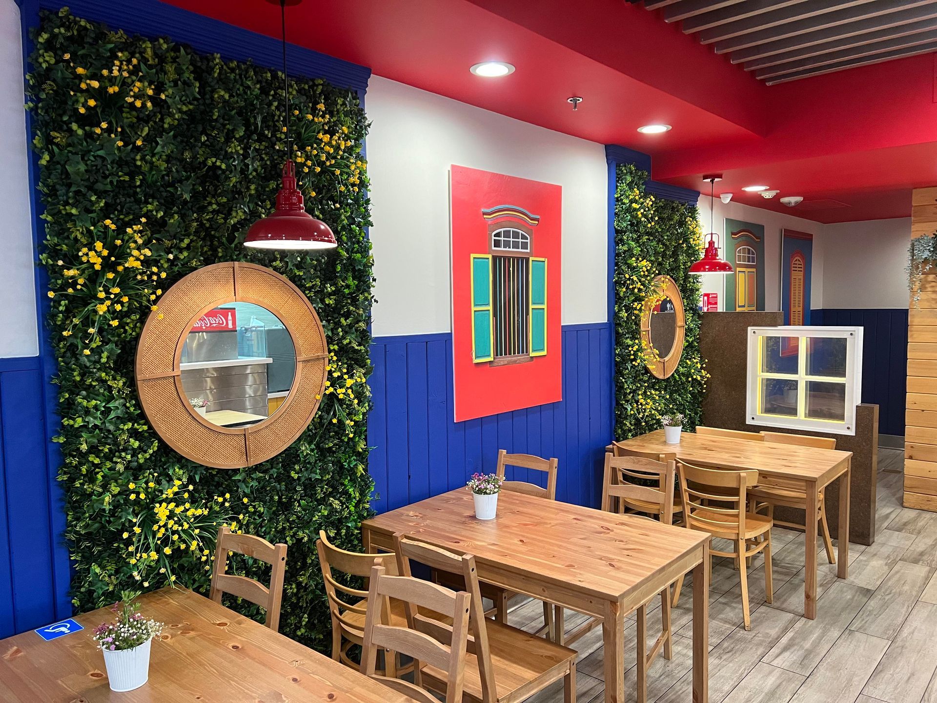 A restaurant with wooden tables and chairs and a red ceiling.