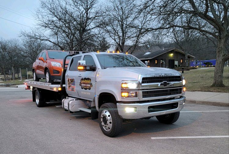 Tow truck with an orange car on its flatbed in a parking lot.
