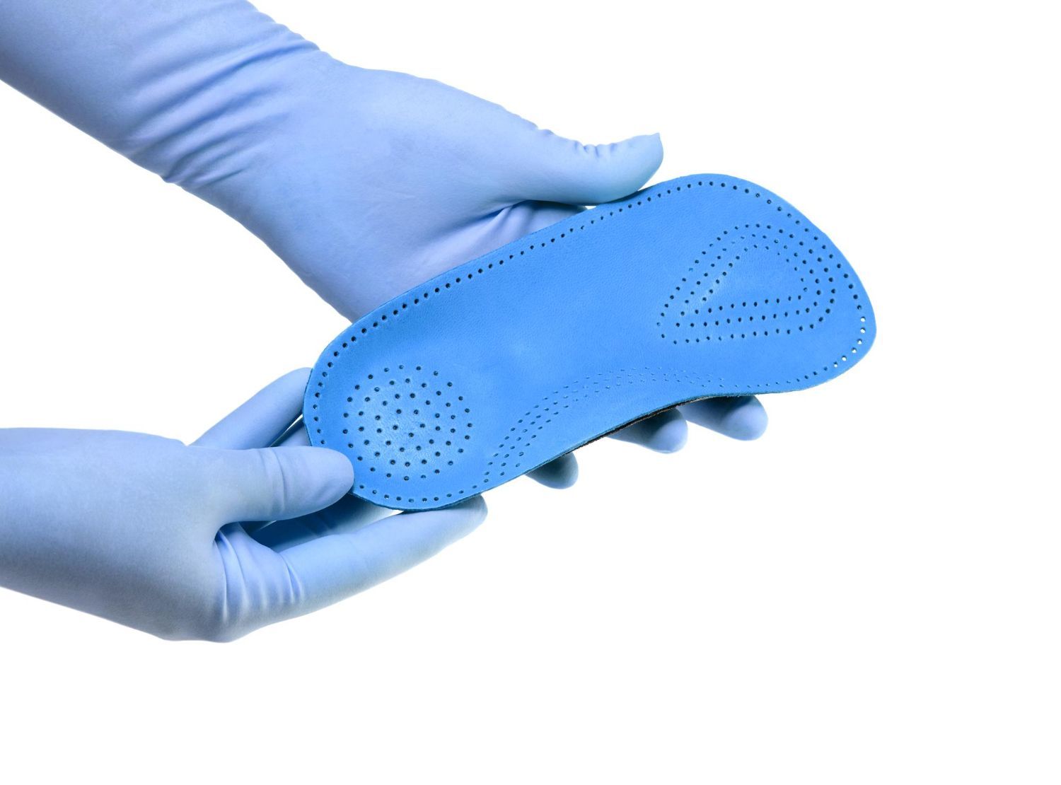 A person wearing blue gloves is holding a blue insole