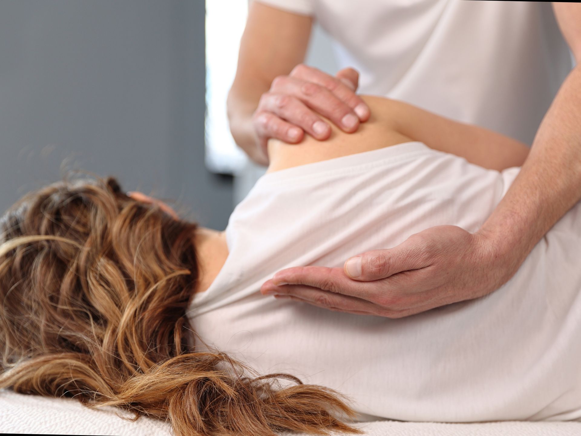 A woman is laying on a bed getting a massage from a man.