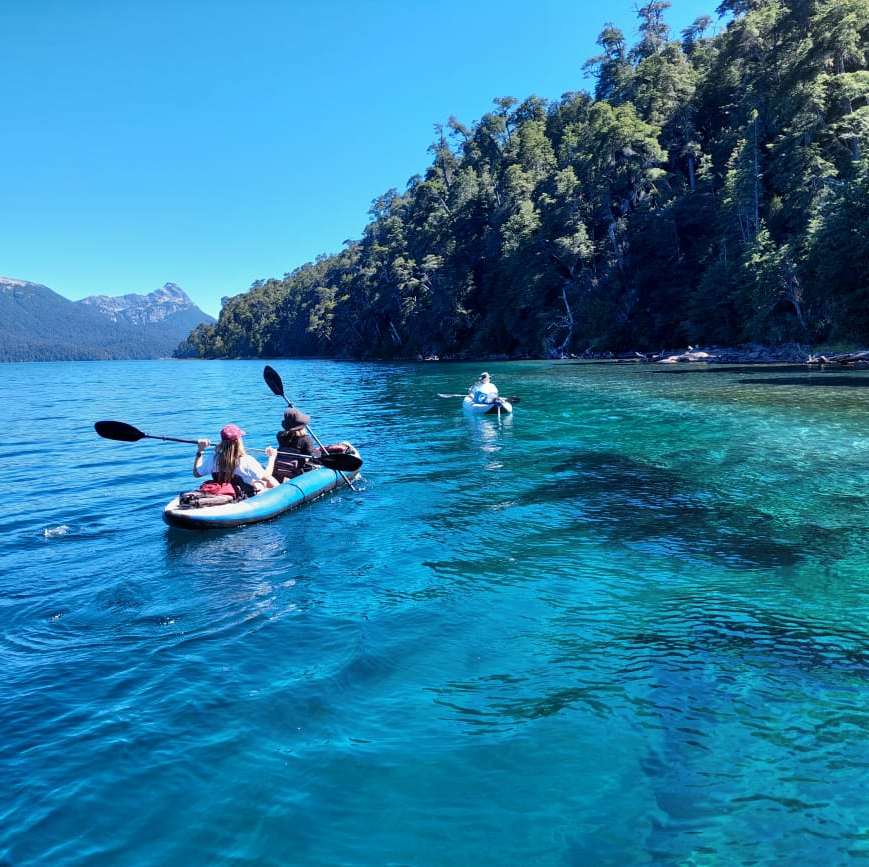 two people in kayaks in a lake with mountains in the background