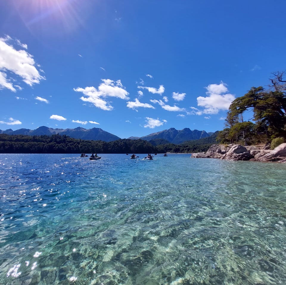 people in kayaks in a lake with mountains in the background
