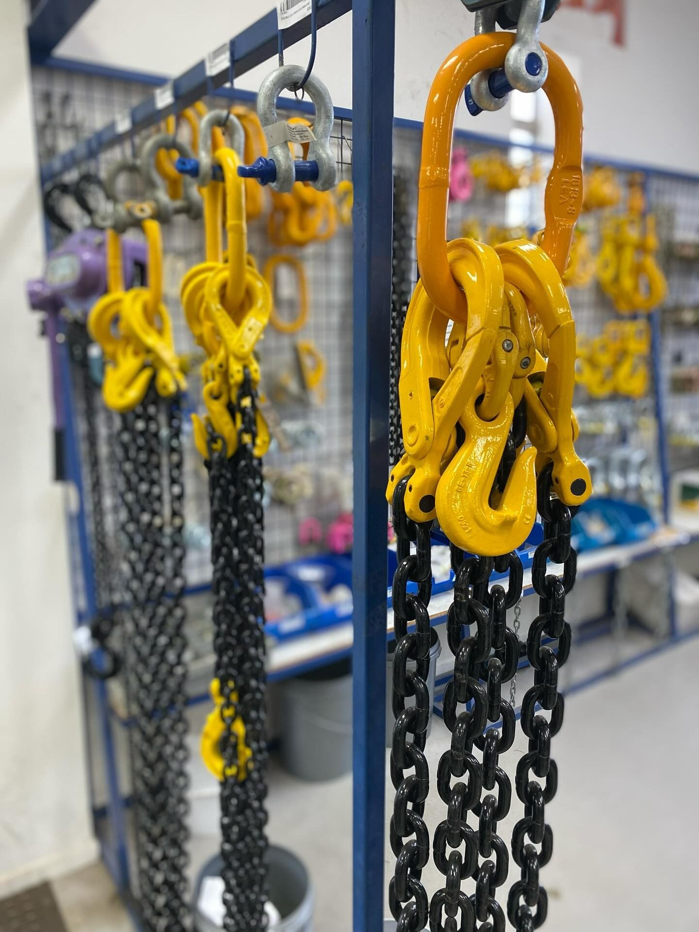 Rows Industrial Black Lifting Chains Yellow Hooks Hanging  on Metal Racks — Air & Lift Gear in Buderim, QLD
