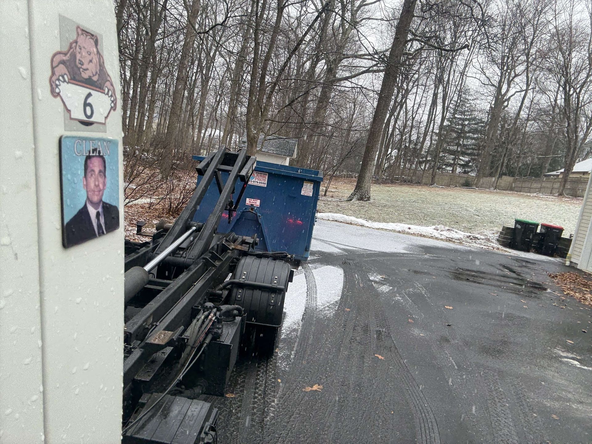 A blue dumpster being loaded onto a truck in darien ct parked on a snowy driveway