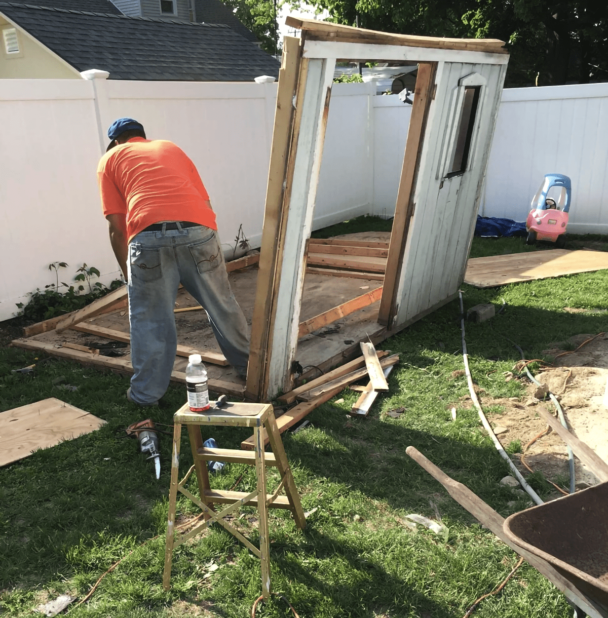 A man in an orange shirt is working on a shed