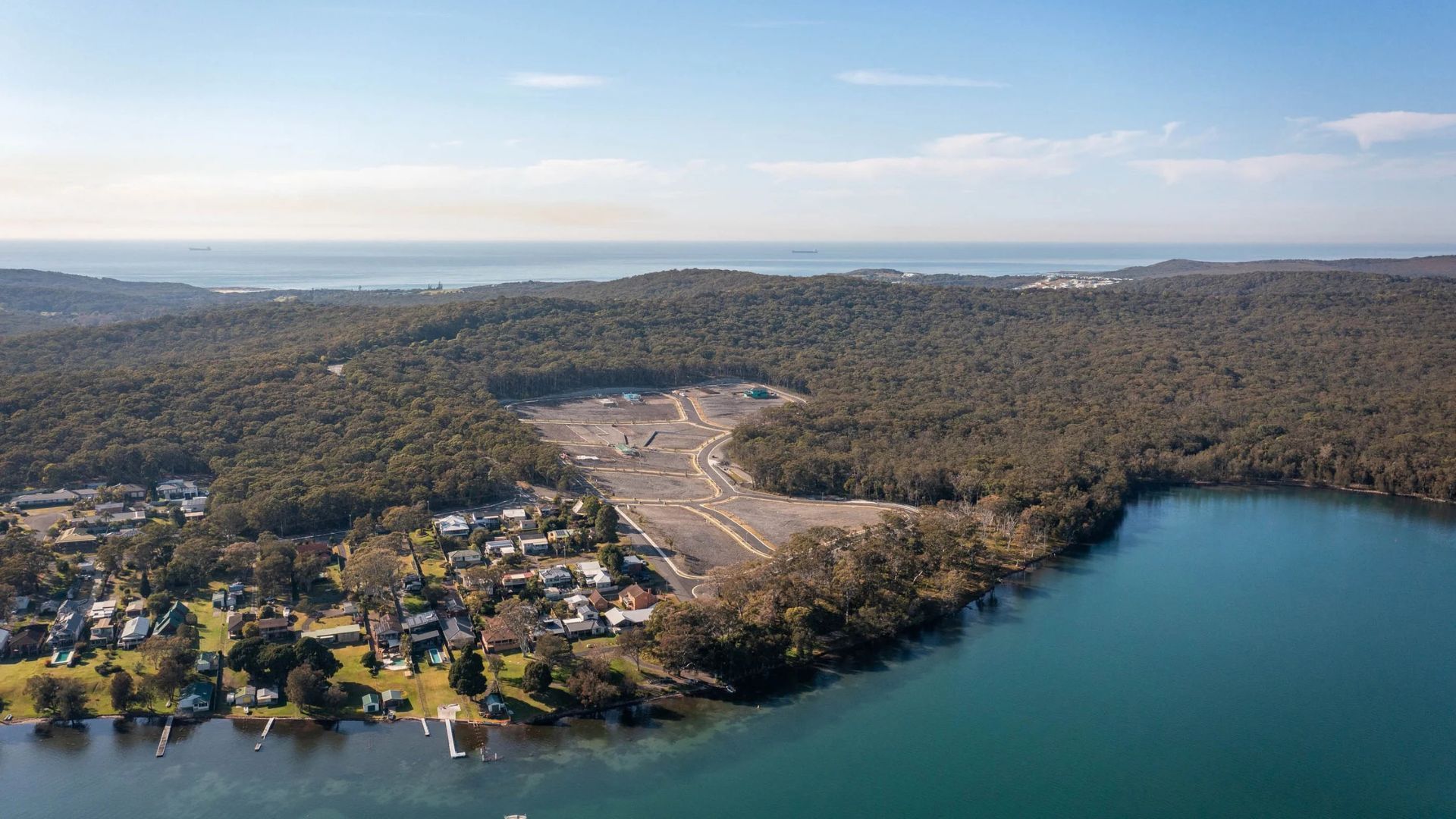 Aerial view of a forested lakeside with a small town and a cleared shoreline area