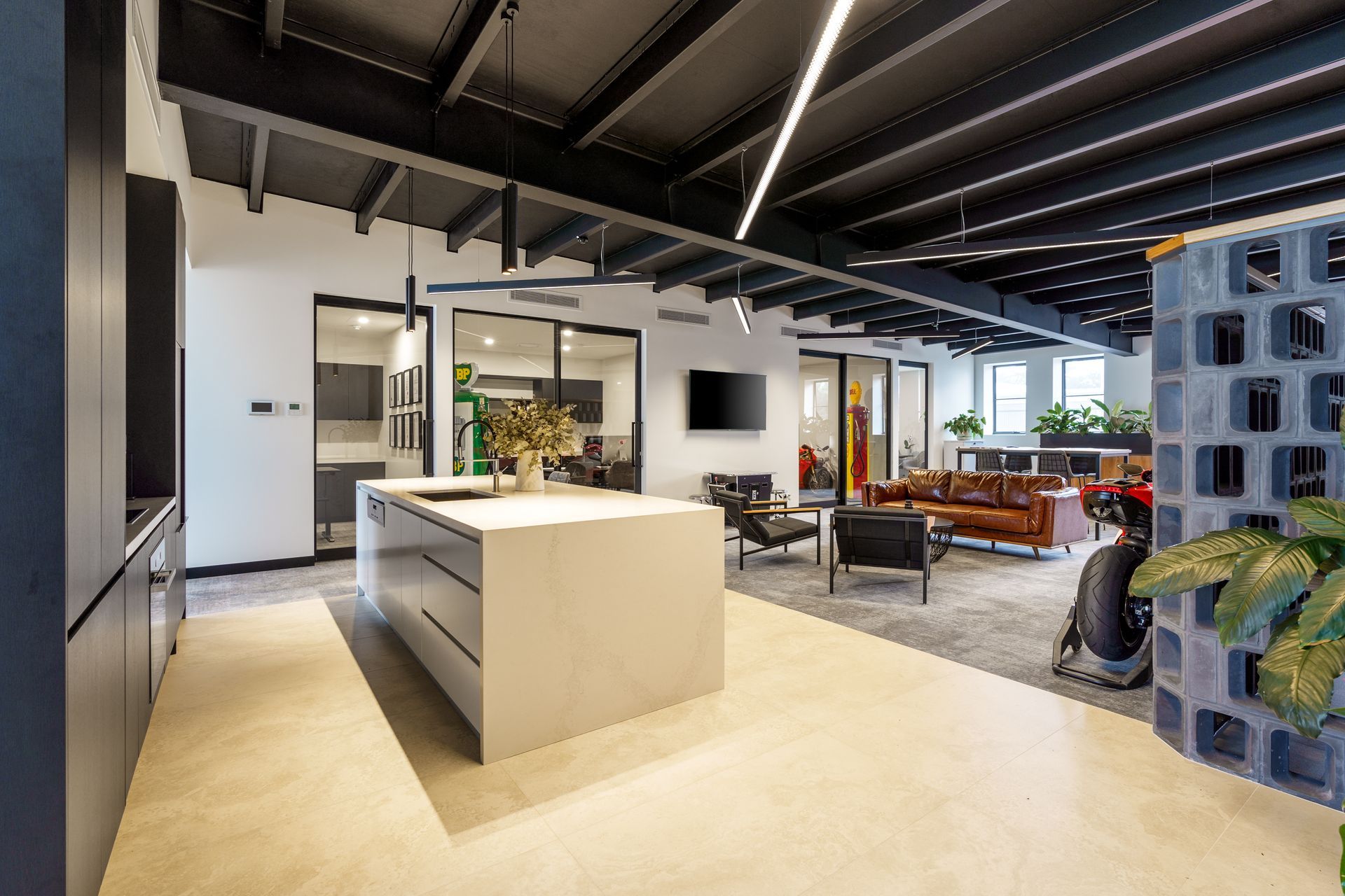 Modern open office interior with central island, seating area, and exposed ceiling beams