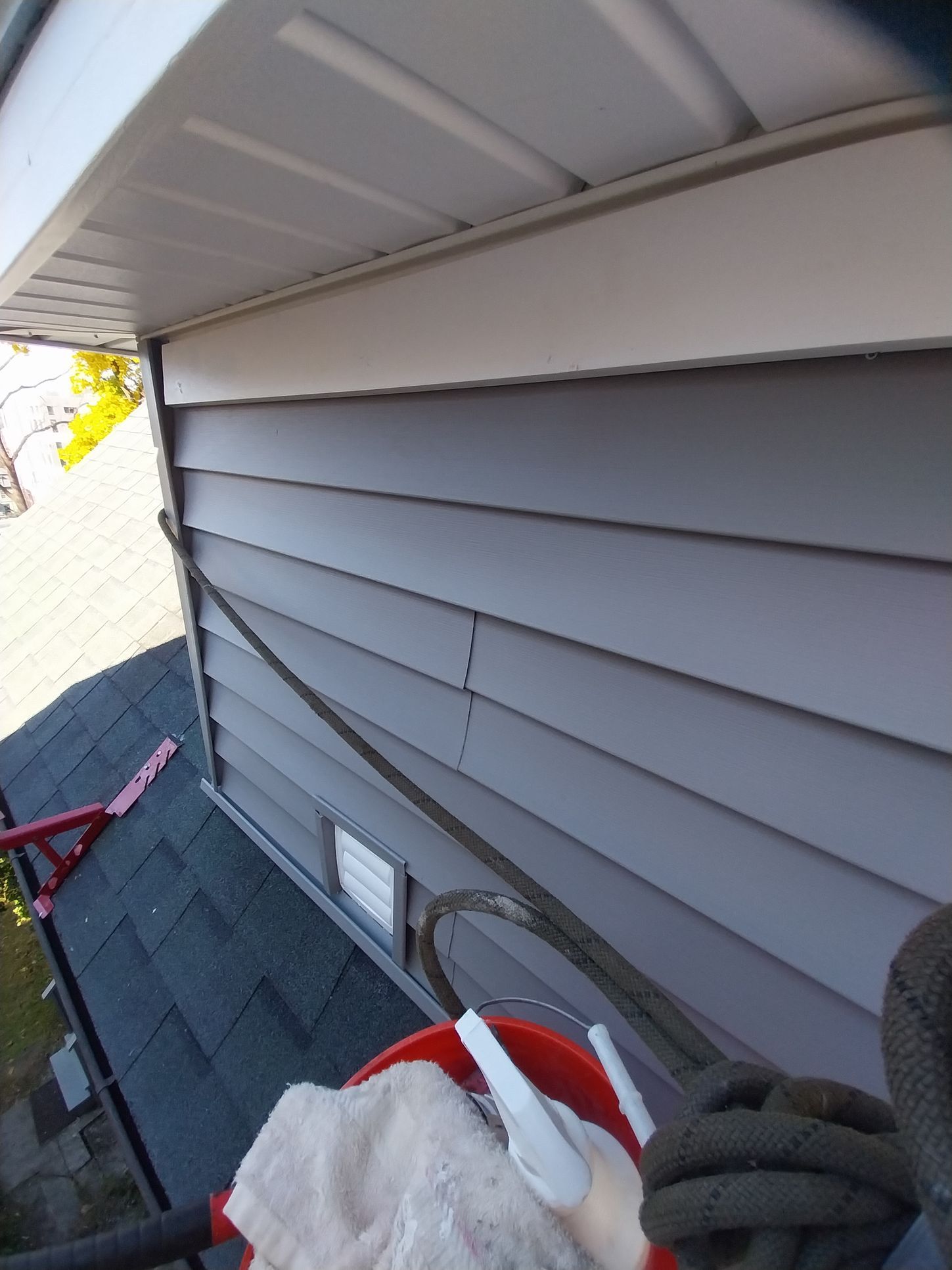 A person is cleaning the side of a house with a mop
