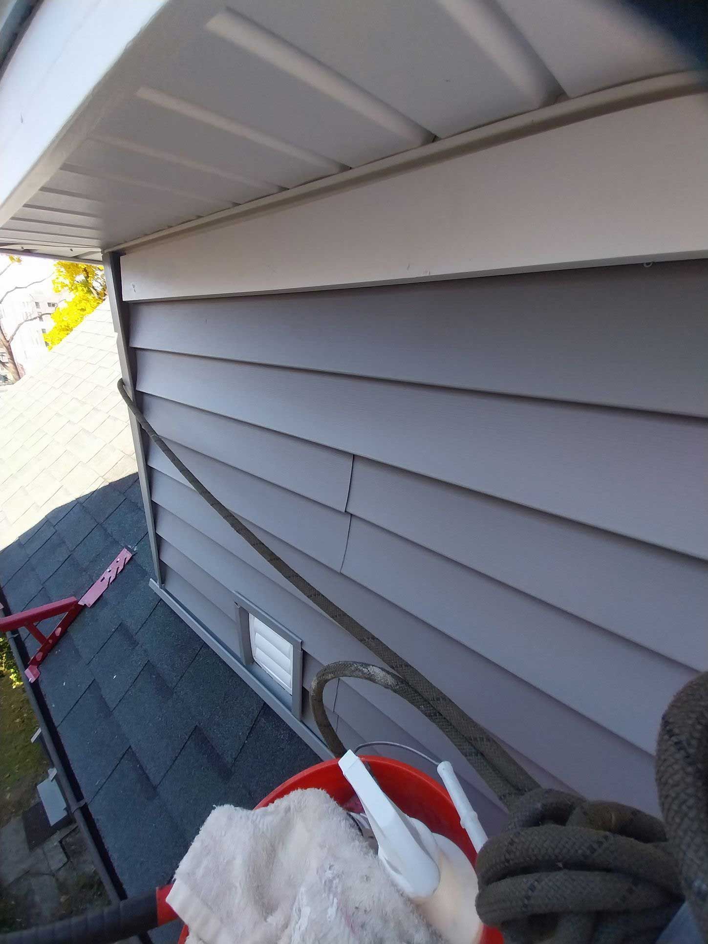 A person is cleaning the side of a house with a mop