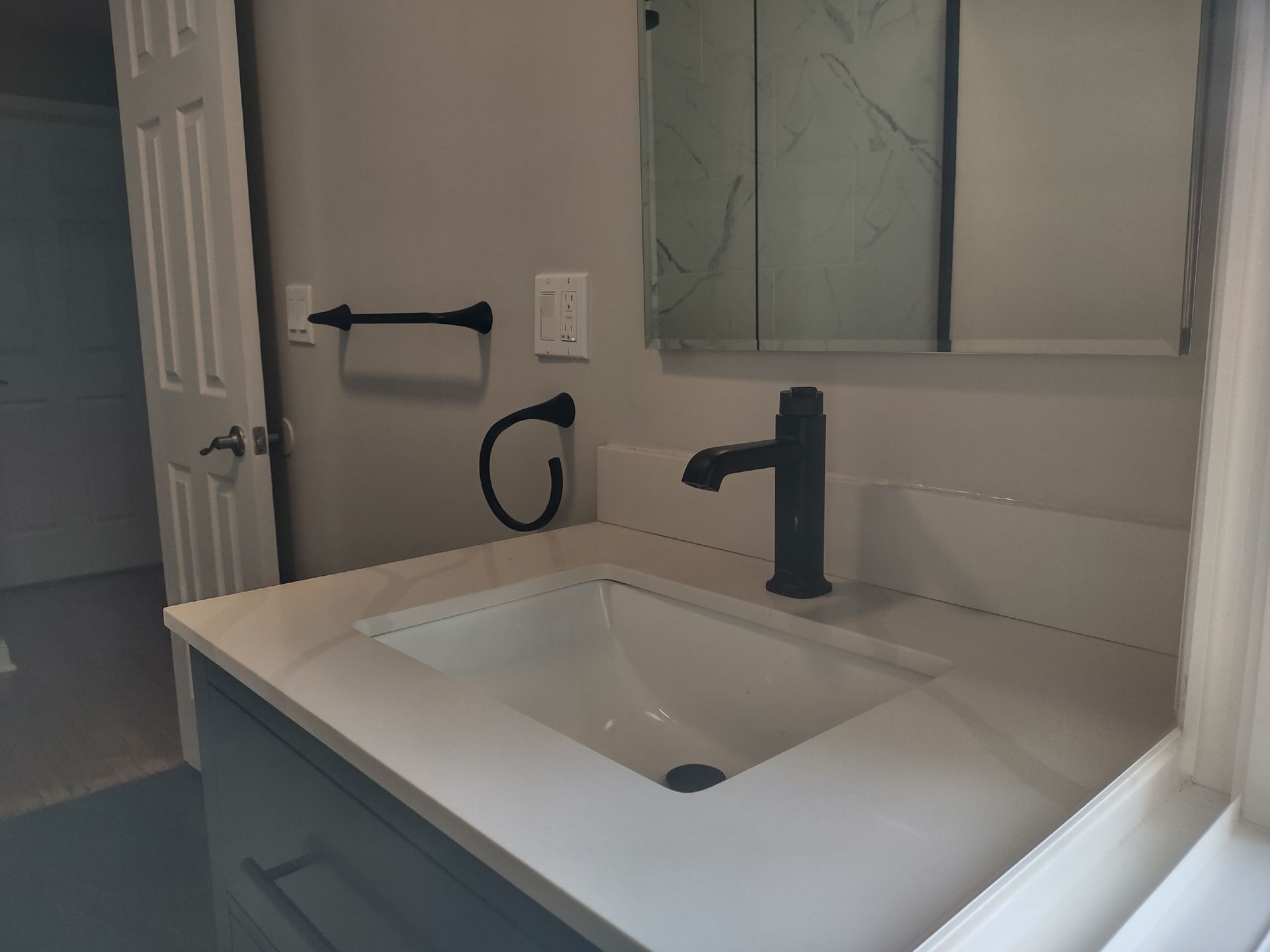 Bathroom with a white countertop, black faucet, and a black towel rack.