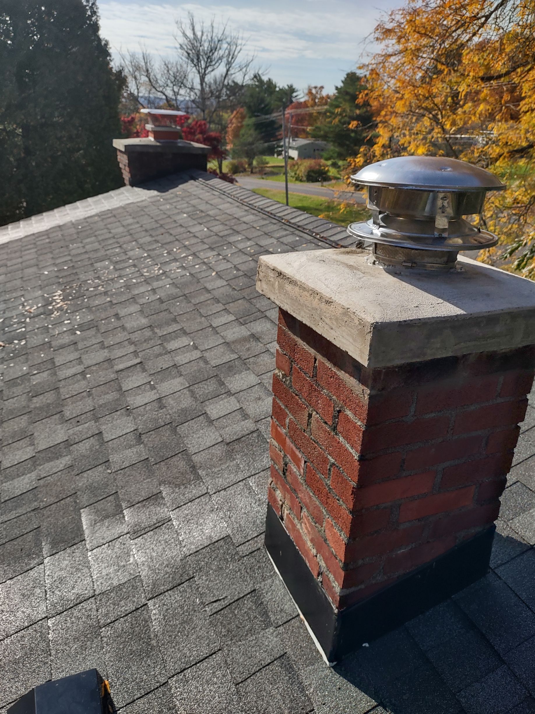 A brick chimney is sitting on top of a roof.