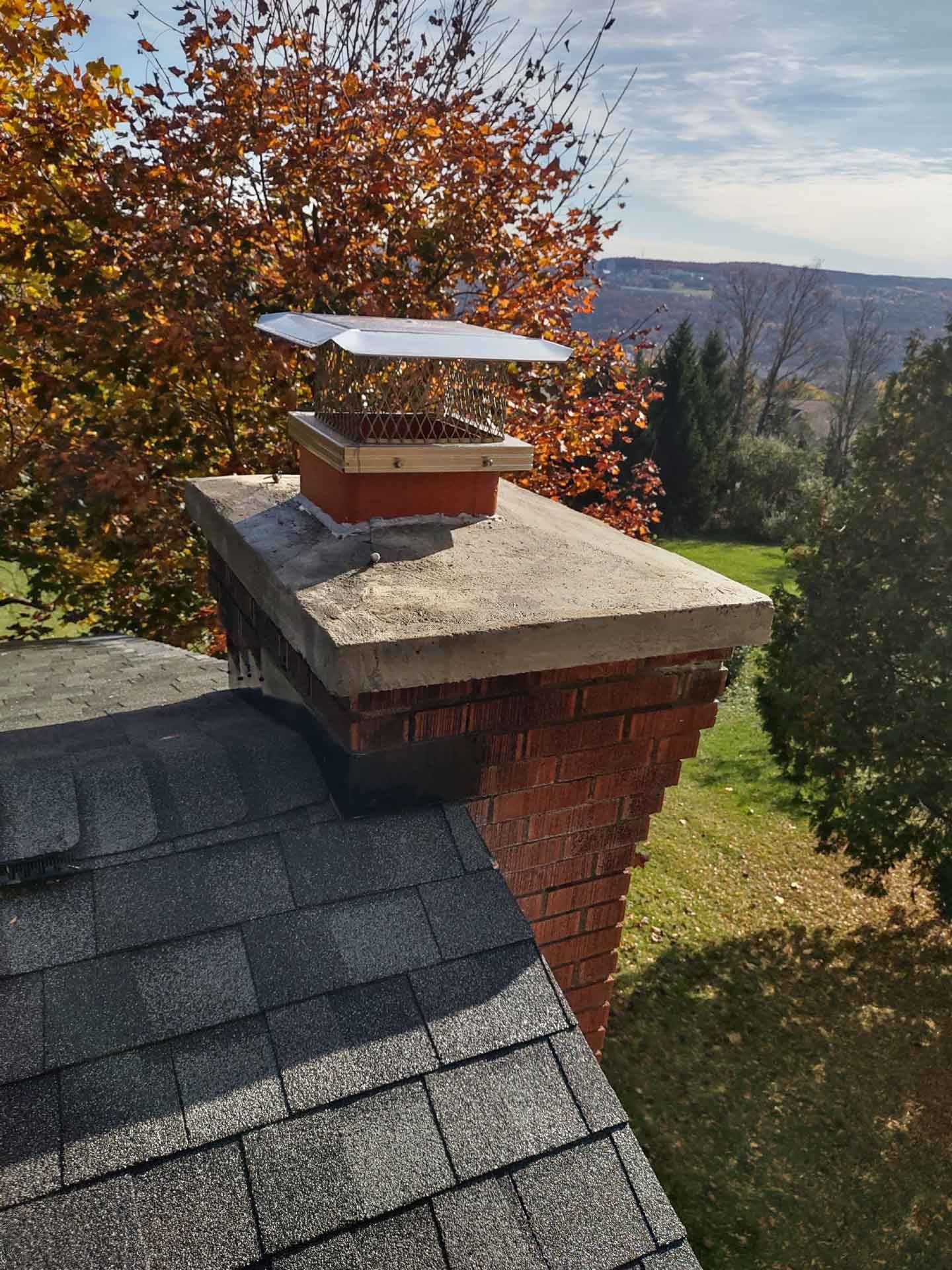 A chimney on top of a roof with a tree in the background.