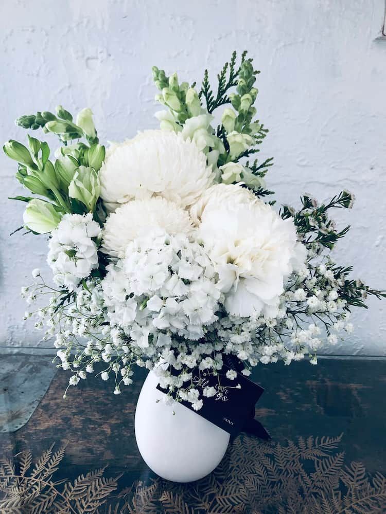 A Vase Filled With White Flowers and Baby 's Breath on a Table — Clover Country Flowers and Gifts In Highfields, QLD
