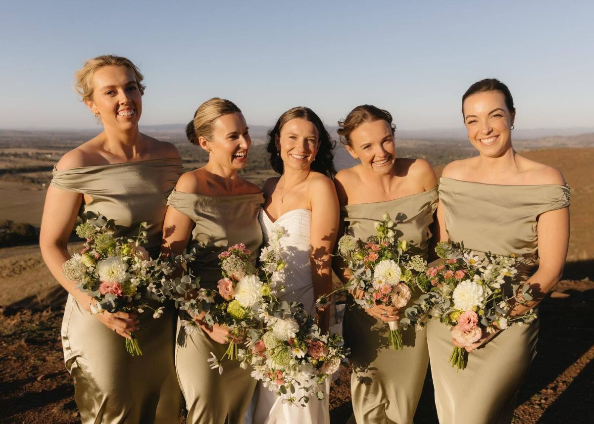 A Bride and Her Bridesmaids Are Posing for a Picture on Top of a Hill — Hello Poppy Lane Florist in Rutherglen, NSW