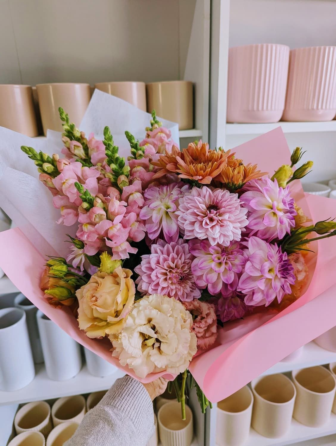A Person is Holding a Bouquet of Flowers Wrapped in Pink Paper — Hello Poppy Lane Florist In Wodonga, VIC